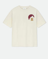 Cream oversized T-shirt with a maroon and gold graphic logo featuring a mountain and the letter R on the chest.