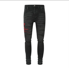 A pair of black skinny jeans with distressed details and red snake embroidery on the left thigh.