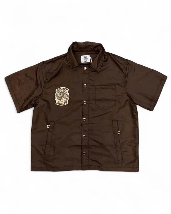 A brown Saint Vanity short-sleeve button-up jacket with a logo patch on the chest, snap buttons, and side pockets.