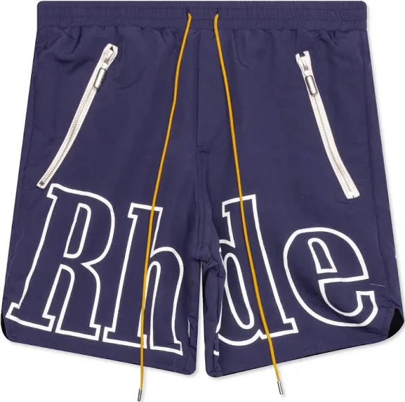 Navy blue Rhude shorts with bold white outlined logo across front, yellow drawstrings, and two slanted zippered pockets with silver pulls.