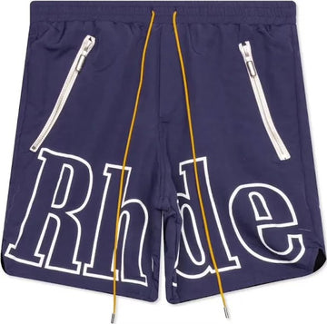 Navy blue Rhude shorts with bold white outlined logo across front, yellow drawstrings, and two slanted zippered pockets with silver pulls.