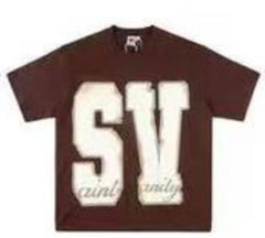A brown Saint Vanity t-shirt with large "SV" lettering on the front and "saint vanity" text in a smaller font below.