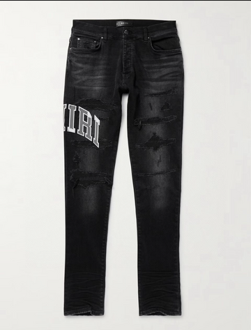 Black distressed slim-fit jeans with rips and white "AMIRI" text on the left thigh, featuring front and back pockets.