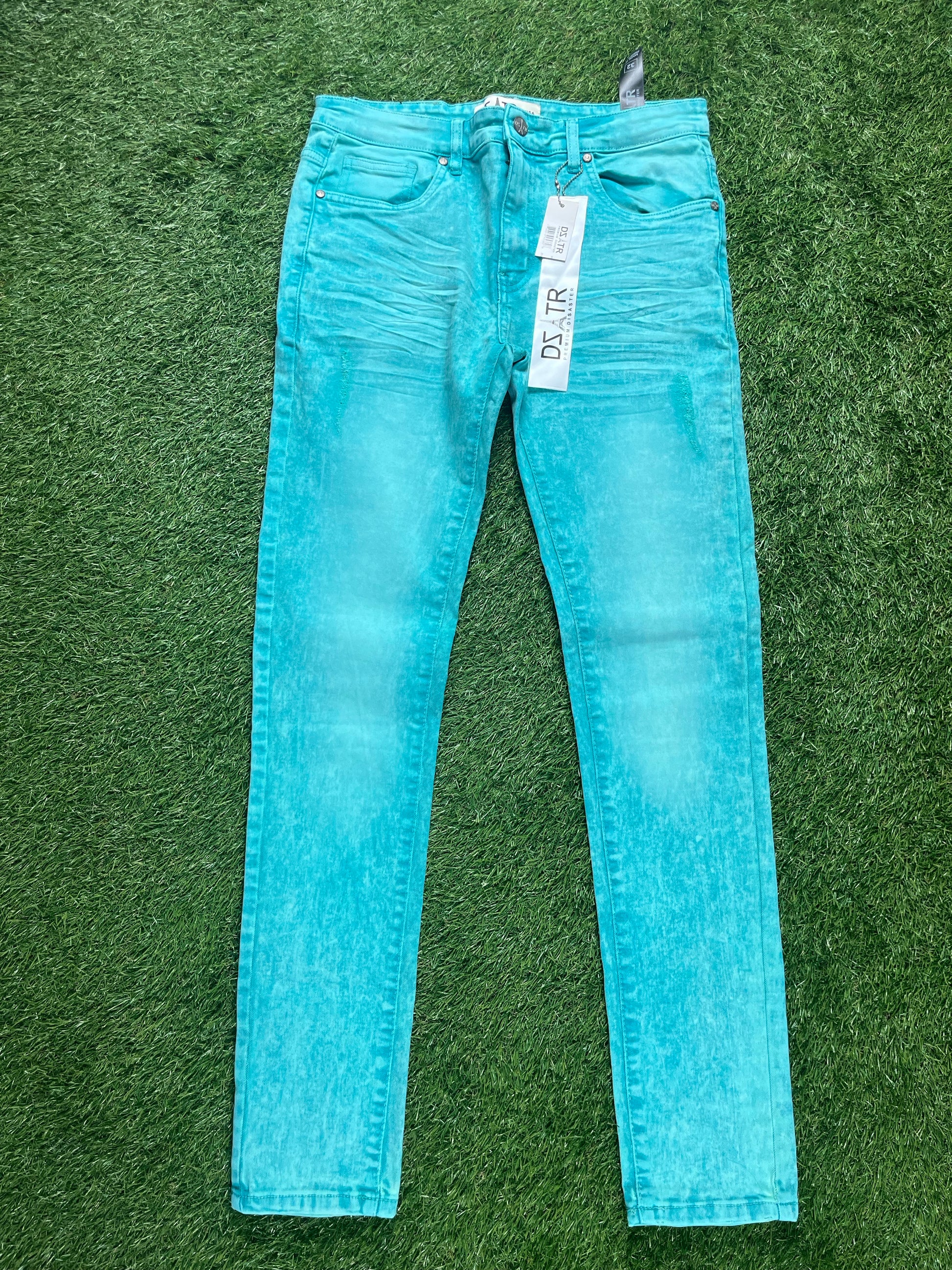 A pair of bright turquoise skinny jeans with a faded look, hanging with price tags still attached.
