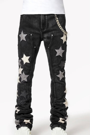 Black jeans with large star-shaped patches in shades of gray and silver, accompanied by a chain accessory on the side.