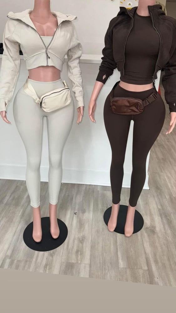 Two mannequins showcasing matching outfits: a white cropped zip-up jacket with leggings and a brown zip-up jacket with leggings.