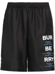 A pair of black shorts with "BURBERRY" branding and various city coordinates printed in blue text along the side.