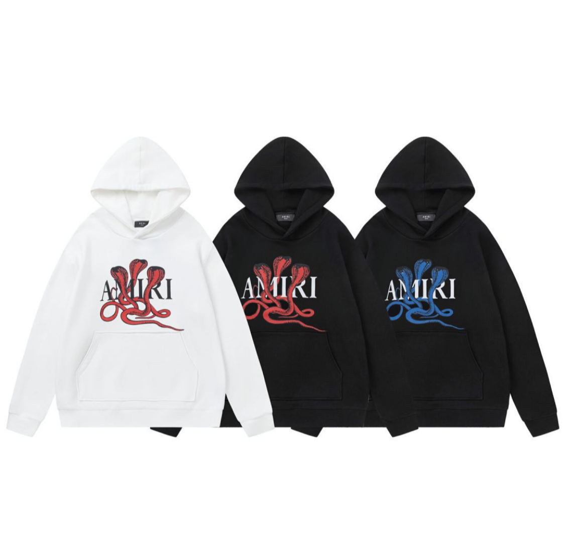 Three AMIRI hoodies in white and black with a cobra snake graphic in red and blue, and "AMIRI" logo across the chest.
