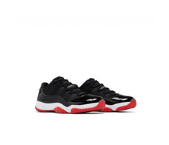 Air Jordan 11 Retro Low sneakers in black with glossy patent leather, white midsole, and red translucent rubber outsole on white background.