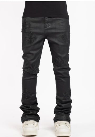 A pair of black leather jeans featuring studded diamond-shaped designs on the thighs and paired with white sneakers.