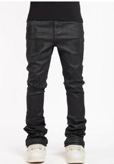 A pair of black leather jeans featuring studded diamond-shaped designs on the thighs and paired with white sneakers.