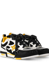 A pair of white and black sneakers with yellow accents, featuring a bold design, mesh panels, and a flower logo on the side.