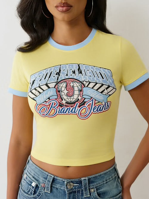 Woman wearing a yellow cropped t-shirt with blue ringer accents and a colorful graphic that says “True Religion Brand Jeans.”