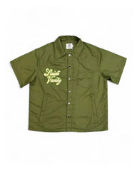 A short-sleeved olive green jacket with a "Saint Vanity" logo embroidered on the left chest, featuring a button-up closure.