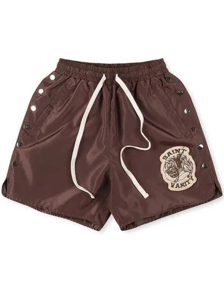 A pair of brown Saint Vanity shorts with a logo patch on the front, snap button details on the sides, and an elastic waistband.