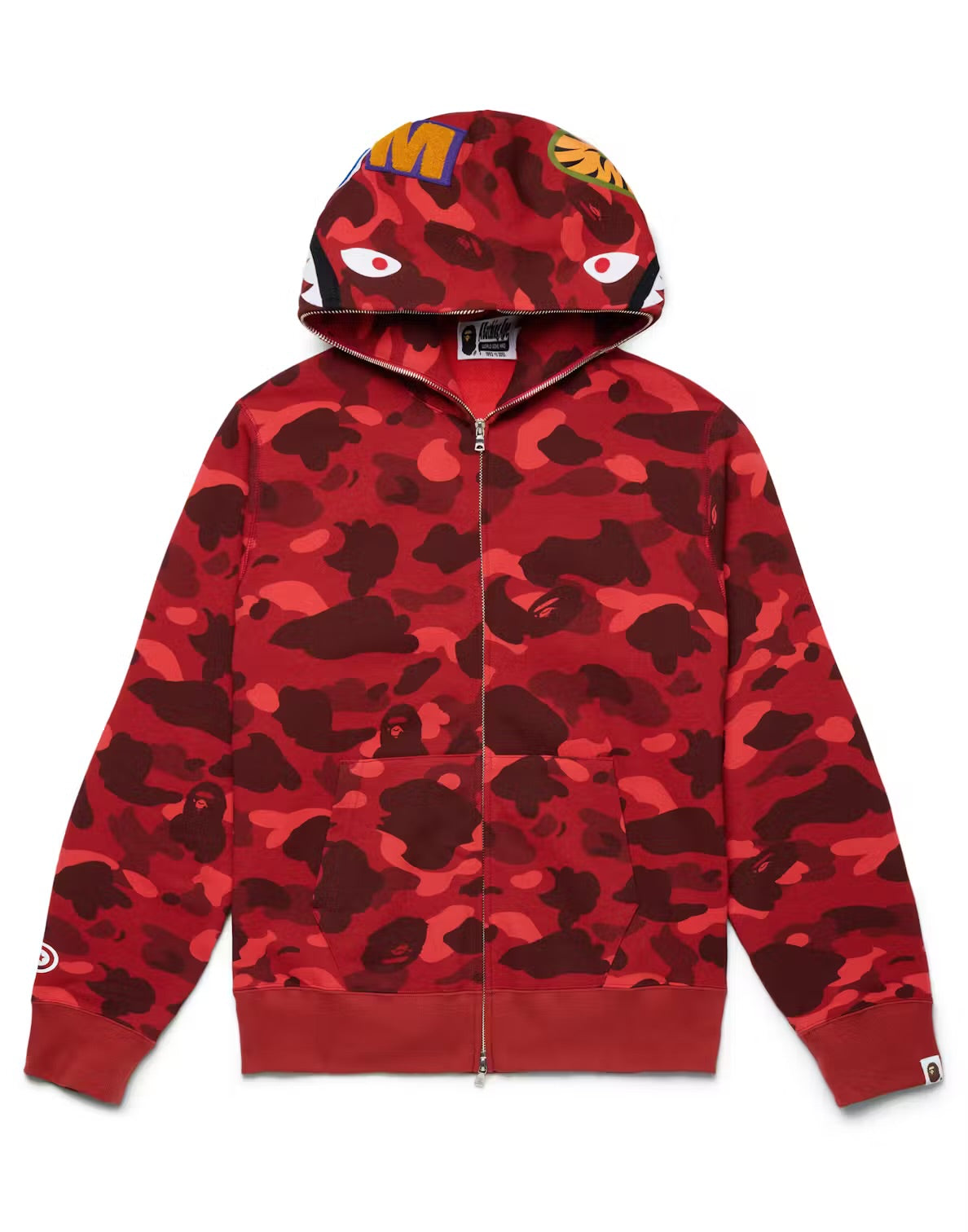 A red BAPE zip-up hoodie with a camouflage pattern, featuring bold eye graphics on the hood and branding on the sleeves.