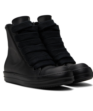 A pair of black high-top sneakers with a leather base, thick knitted laces, and a sleek, minimalist design.