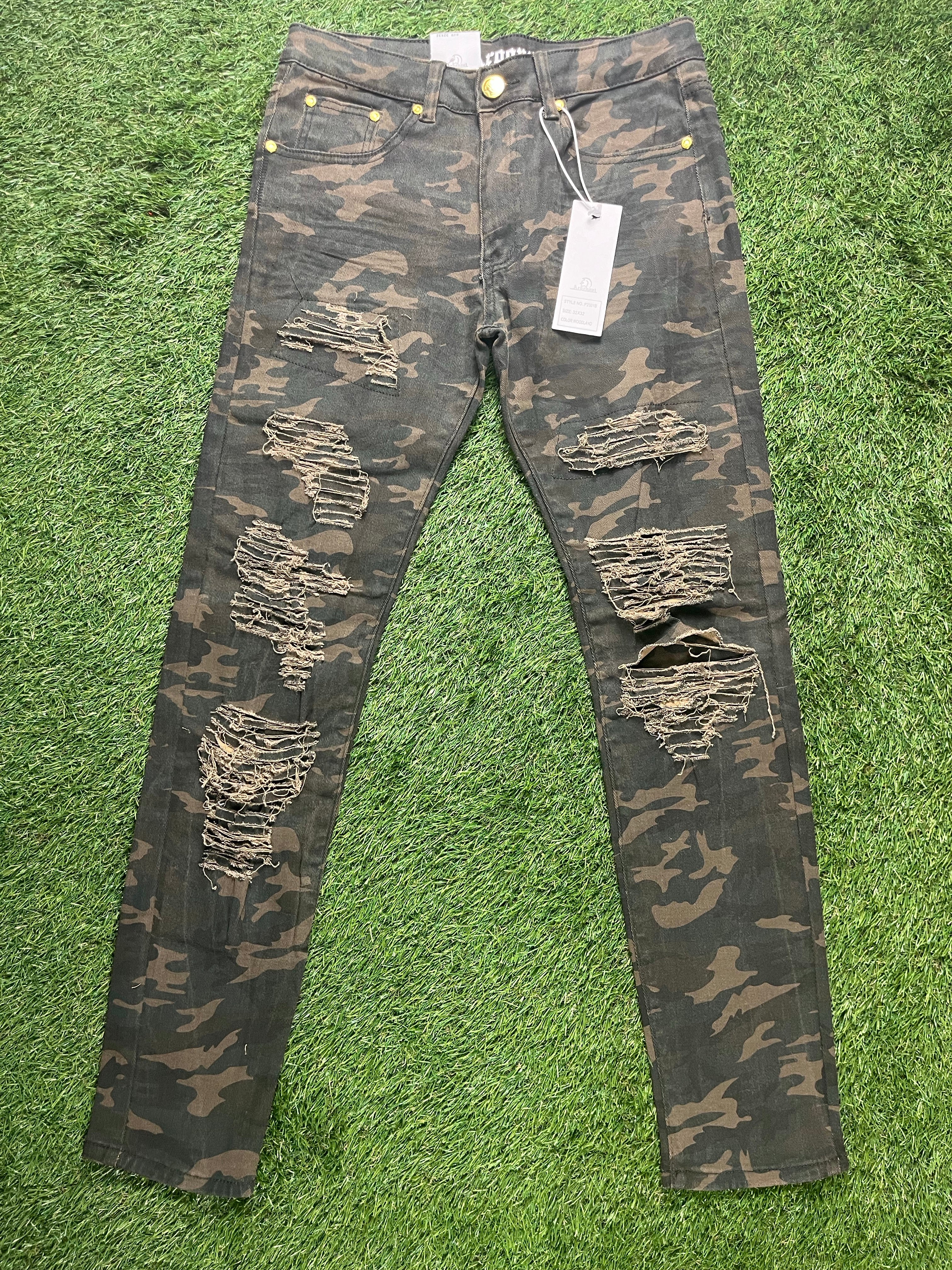A pair of camo-patterned skinny jeans with multiple distressed rips, yellow button details, and price tags attached.