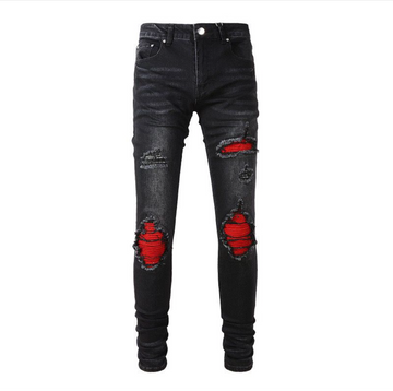 Black ripped skinny jeans with red fabric showing through large distressed patches on front, displayed on white background.