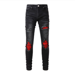 Black ripped skinny jeans with red fabric showing through large distressed patches on front, displayed on white background.
