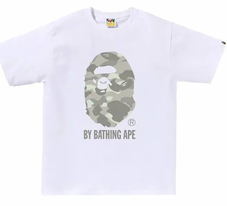 A white t-shirt featuring the BAPE logo, with a camouflage ape face design and the text "BY BATHING APE" underneath.