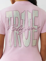 Back view of a woman wearing a pink T-shirt with large rhinestone-studded “TRUE TRUE” text and cursive “Religion” across the back.