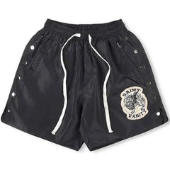 A pair of black Saint Laurent shorts with side snap buttons, an elastic waistband, and a patch logo on the front.