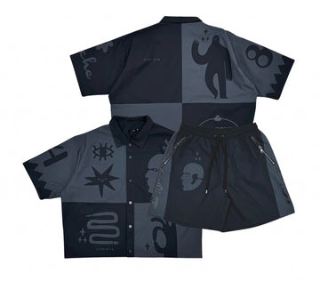 A black and grey patterned shirt and shorts set with various bold graphic designs like eyes, faces, and stars on the fabric.