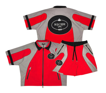A red and grey tracksuit set, featuring a zip-up jacket with a "Riche" logo on the back and matching shorts with similar detailing.
