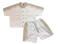 Two-piece cream and beige button-up shirt and shorts set with a subtle logo design, drawstring waist, and contrasting shoulder panels.