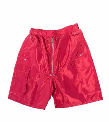Bright red shiny nylon shorts with elastic waistband, silver zipper front, and large flap pockets on each side against white.